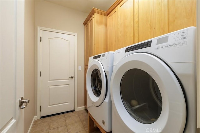 laundry area featuring washer and dryer, cabinets, and light tile patterned floors