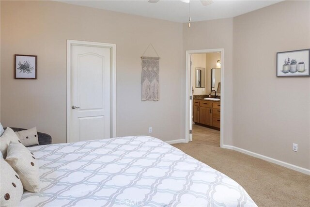 bedroom with light carpet, ceiling fan, ensuite bathroom, and sink