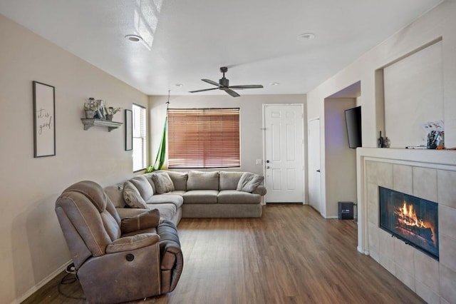 living room featuring ceiling fan, a tiled fireplace, and hardwood / wood-style floors