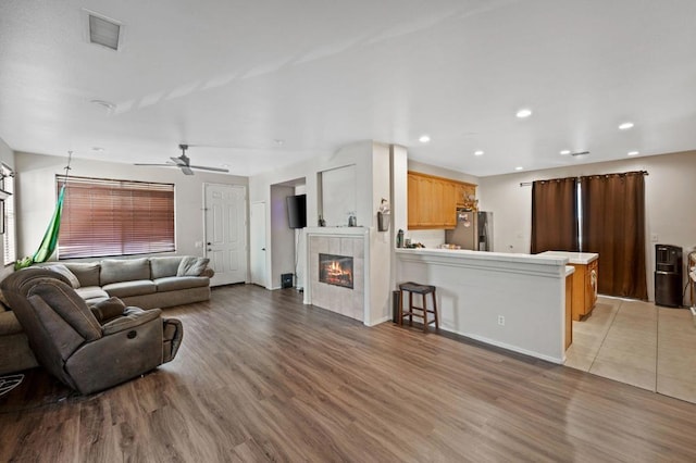 living room featuring light hardwood / wood-style flooring, a fireplace, and ceiling fan