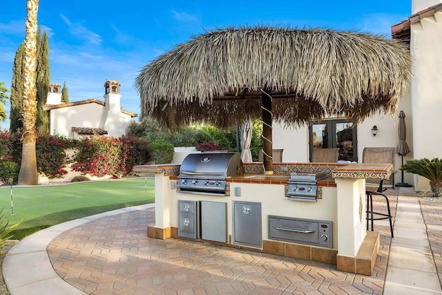 view of patio with exterior bar, an outdoor kitchen, and area for grilling