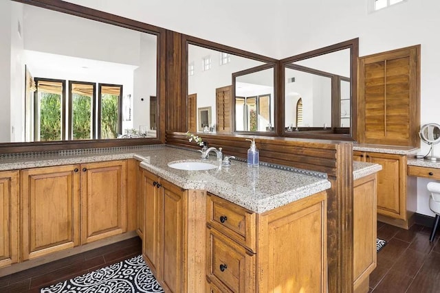 kitchen featuring light stone countertops, dark hardwood / wood-style floors, kitchen peninsula, and sink