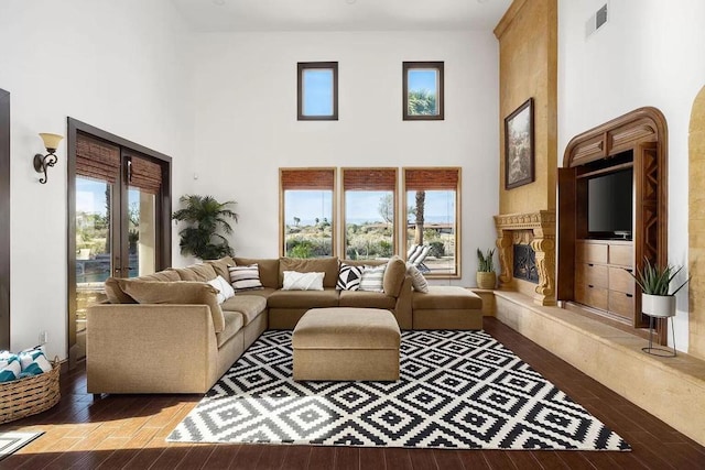 living room with a high ceiling, light wood-type flooring, and a premium fireplace