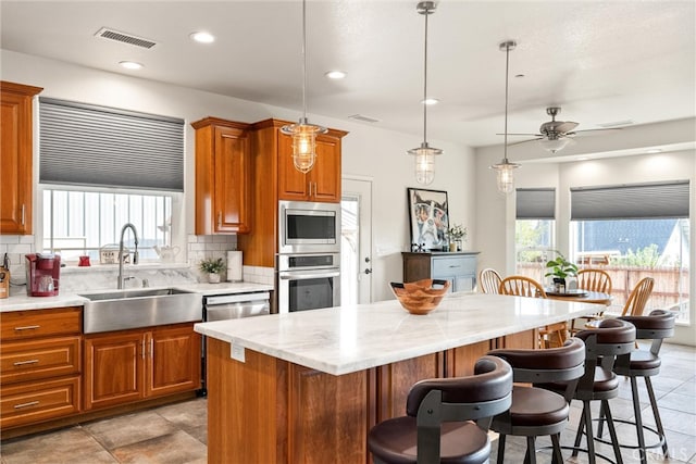 kitchen featuring a kitchen island, stainless steel appliances, sink, and backsplash