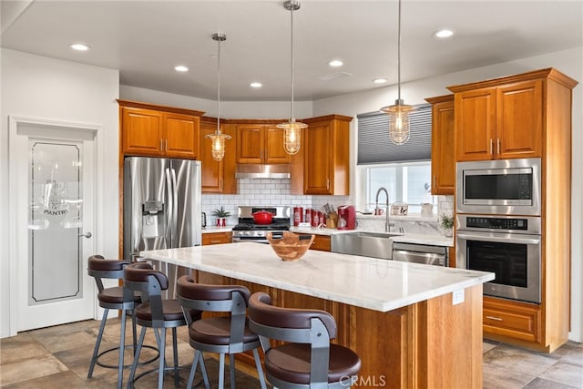 kitchen featuring tasteful backsplash, a breakfast bar, stainless steel appliances, pendant lighting, and a center island