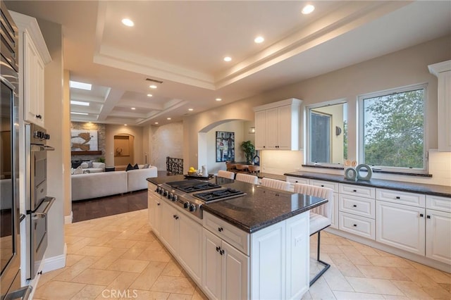 kitchen with a kitchen bar, a center island, stainless steel appliances, and white cabinetry