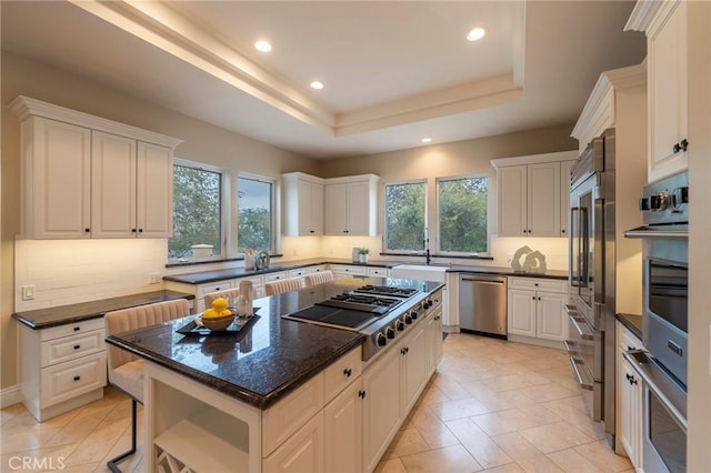 kitchen with a kitchen island, a healthy amount of sunlight, white cabinetry, and appliances with stainless steel finishes