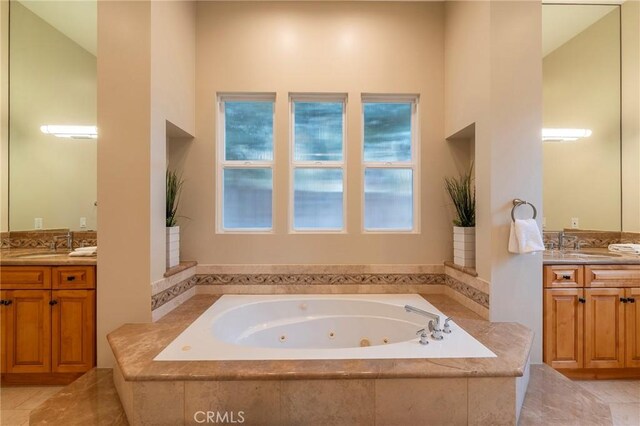 bathroom with tiled tub, a towering ceiling, and vanity