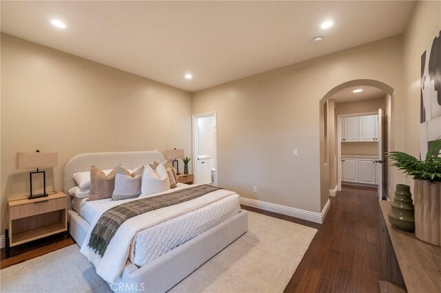 bedroom with connected bathroom and dark wood-type flooring