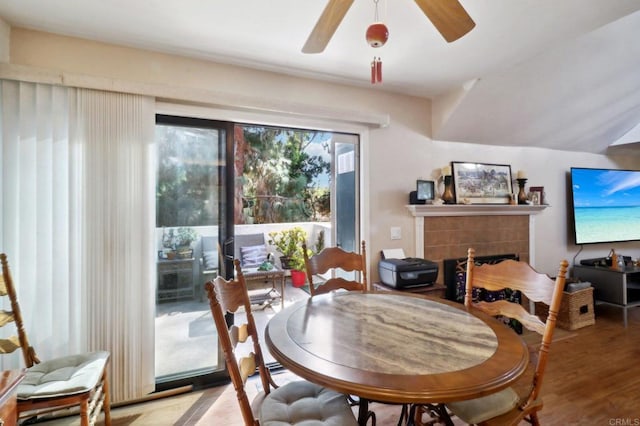 dining room with hardwood / wood-style floors, a fireplace, and ceiling fan