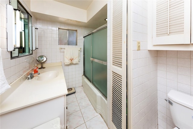 full bathroom featuring bath / shower combo with glass door, tile walls, toilet, vanity, and tile patterned floors