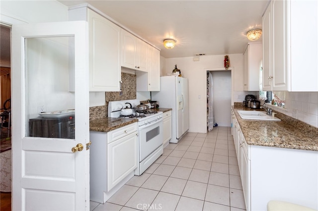 kitchen featuring backsplash, dark stone countertops, sink, white cabinets, and white appliances