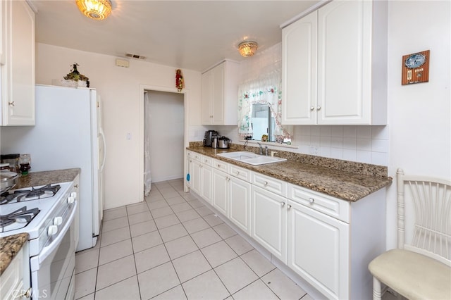 kitchen with white cabinetry, sink, dark stone counters, and white range oven