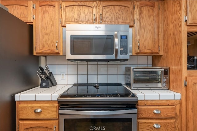 kitchen featuring tile countertops, decorative backsplash, and stainless steel appliances