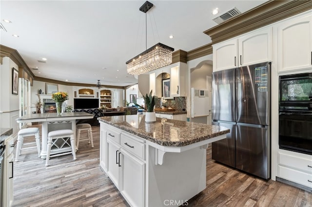 2550 E Jenny Ave, Fresno, CA 93720 - kitchen with a breakfast bar, black appliances, white cabinets, crown molding, and hardwood / wood-style flooring