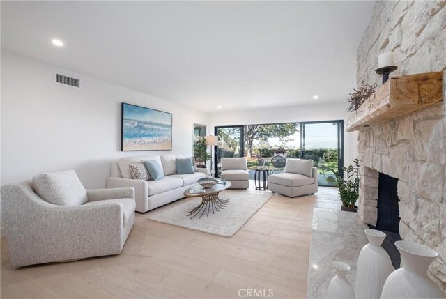 living room featuring light hardwood / wood-style flooring and a stone fireplace