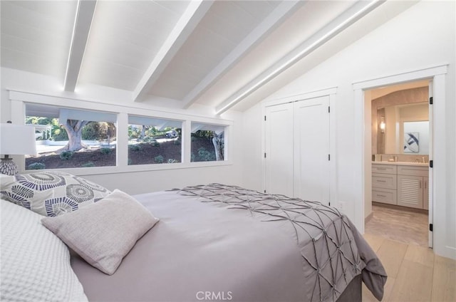 bedroom with vaulted ceiling with beams, ensuite bathroom, and a closet