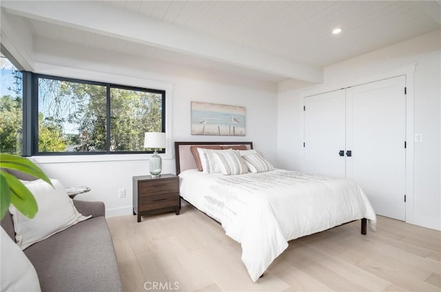 bedroom featuring beam ceiling and light hardwood / wood-style flooring