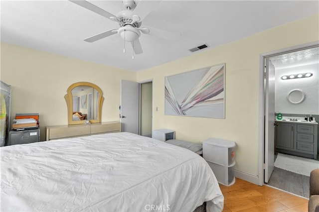 bedroom featuring ceiling fan, light hardwood / wood-style floors, sink, and ensuite bath