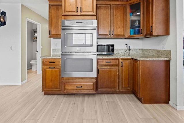 kitchen featuring light stone counters, stainless steel appliances, and light hardwood / wood-style flooring