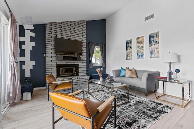 living room with a fireplace, light wood-type flooring, and vaulted ceiling