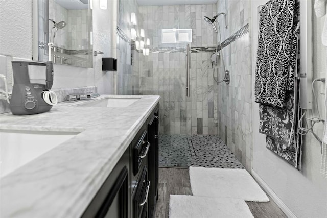 bathroom with vanity, wood-type flooring, and tiled shower