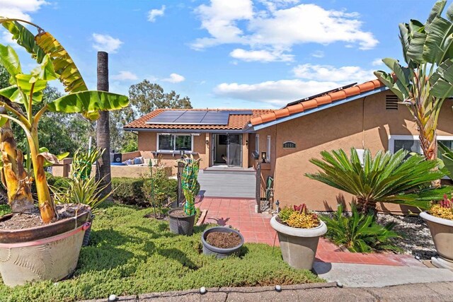 view of front of home with a patio and solar panels