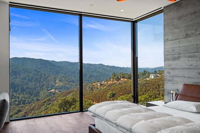 unfurnished bedroom featuring a mountain view, hardwood / wood-style flooring, and floor to ceiling windows