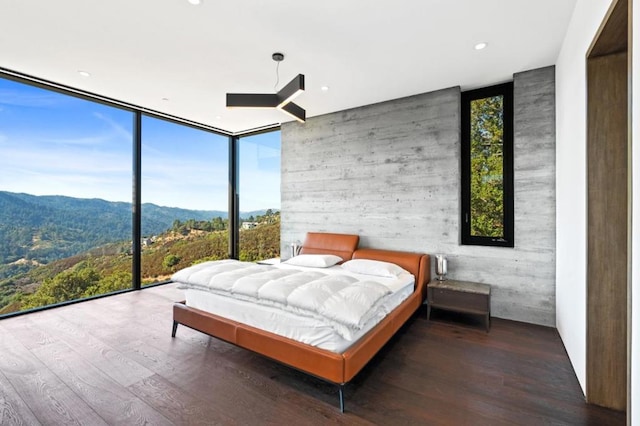 bedroom featuring a mountain view, dark wood-type flooring, and floor to ceiling windows