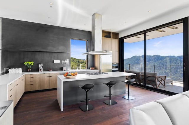 kitchen featuring stainless steel gas stovetop, a center island, light brown cabinetry, island exhaust hood, and a mountain view