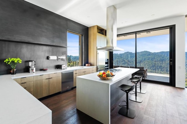 kitchen with appliances with stainless steel finishes, a kitchen island, dark hardwood / wood-style flooring, a kitchen breakfast bar, and a mountain view