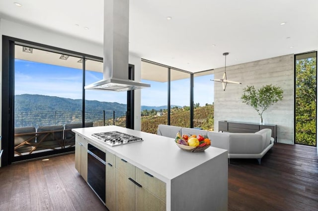 kitchen featuring hanging light fixtures, dark hardwood / wood-style flooring, a mountain view, a center island, and island range hood