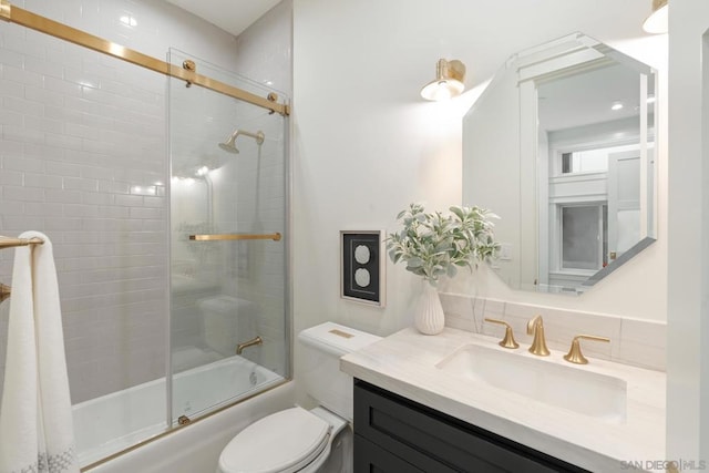 full bathroom featuring combined bath / shower with glass door, vanity, and toilet