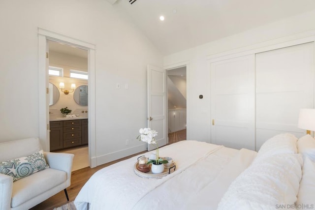 bedroom featuring hardwood / wood-style floors, ensuite bathroom, vaulted ceiling, and a closet