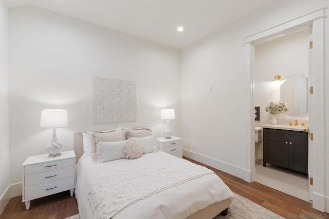 bedroom featuring dark hardwood / wood-style flooring, ensuite bath, and sink