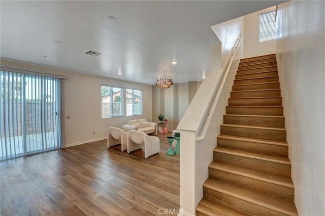 stairway with hardwood / wood-style floors and a notable chandelier