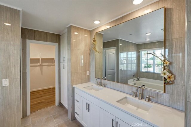 bathroom featuring tile patterned flooring, vanity, tile walls, and a washtub