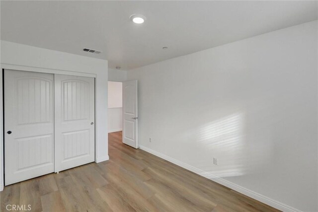 unfurnished bedroom with a closet and light hardwood / wood-style floors