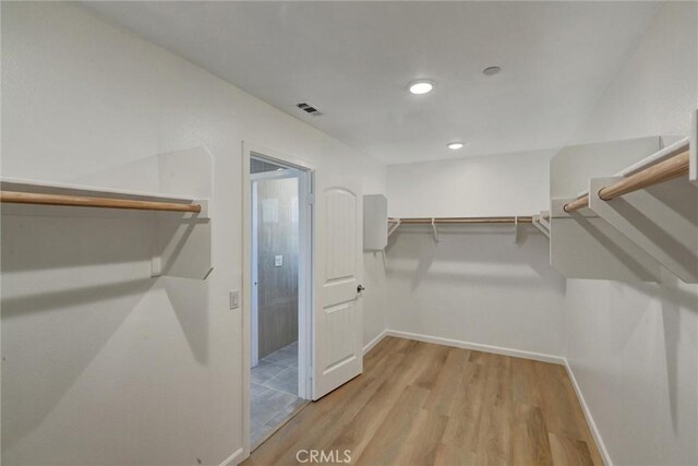 walk in closet with light hardwood / wood-style floors