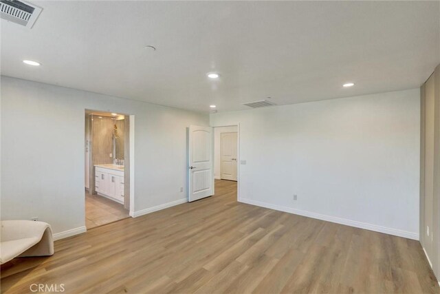 unfurnished bedroom featuring connected bathroom and light wood-type flooring