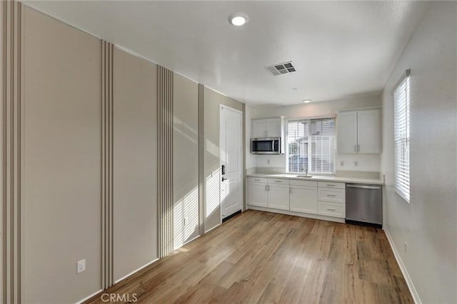 kitchen featuring light wood-type flooring, stainless steel appliances, and white cabinetry