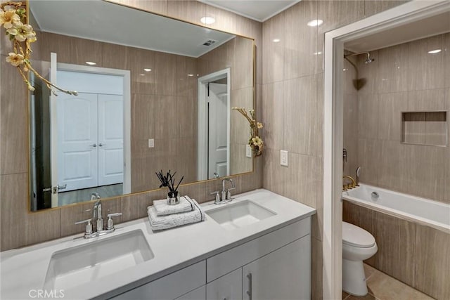 full bathroom with vanity, tiled shower / bath combo, toilet, and tile walls