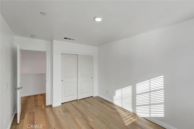 unfurnished bedroom featuring light wood-type flooring and a closet