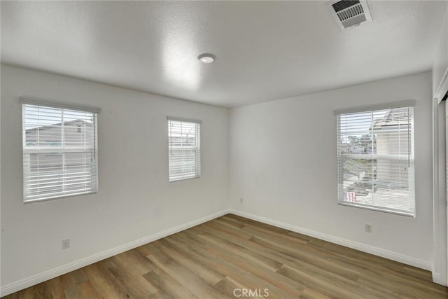 unfurnished room with hardwood / wood-style flooring and a wealth of natural light