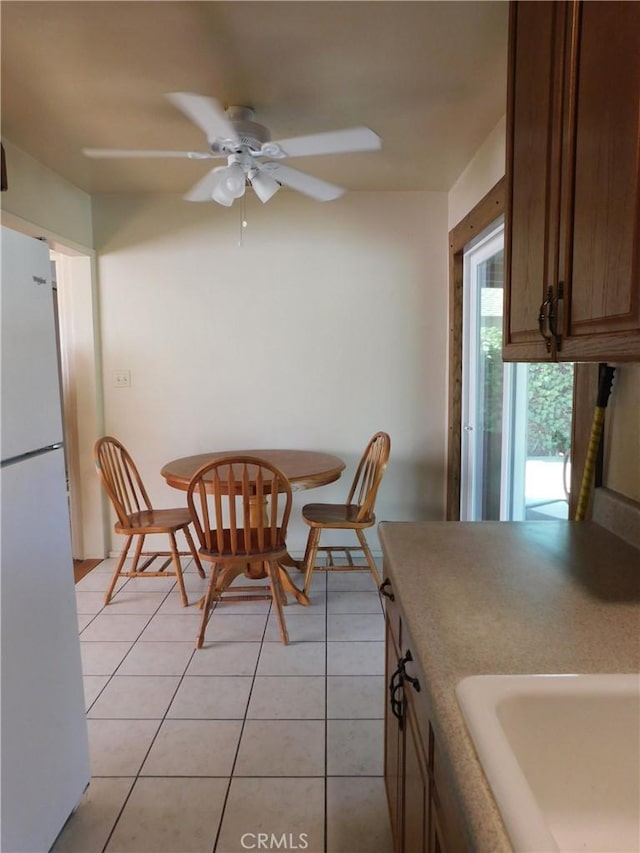 tiled dining space with ceiling fan and sink