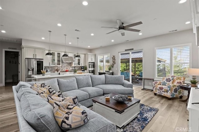 living room with ceiling fan, a healthy amount of sunlight, sink, and light hardwood / wood-style flooring