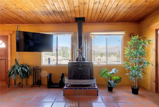 living room featuring a wood stove, wooden ceiling, and a wealth of natural light