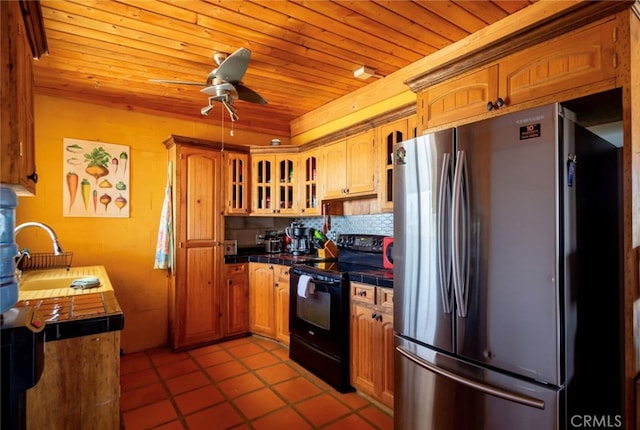 kitchen featuring black range with electric cooktop, stainless steel fridge, tile countertops, and wooden ceiling