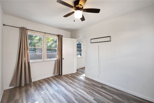 unfurnished room with hardwood / wood-style flooring, a wall unit AC, and ceiling fan