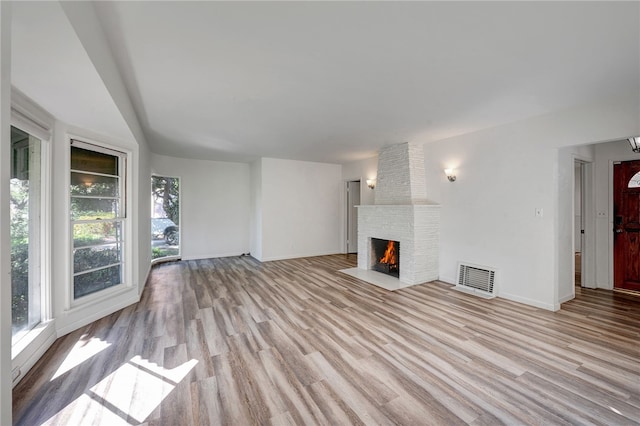 unfurnished living room with light hardwood / wood-style floors and a brick fireplace